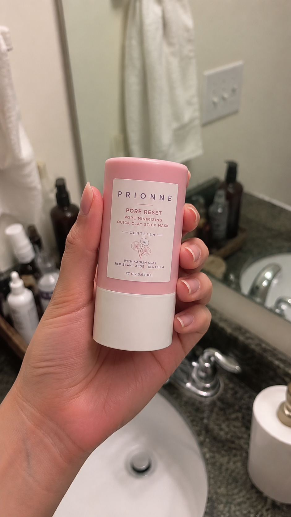 Female customer hand holding Prionne near a bathroom sink